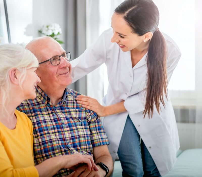 smiling-nurse-talking-with-senior-couple-during-home-visit